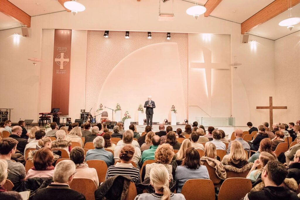 Gottesdienstsaal der Evangelischen Freikirche Köln mit Zuhörern während einer Predigt