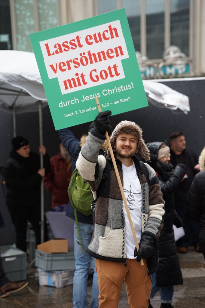 Teilnehmer mit Schild „Lasst euch versöhnen mit Gott“